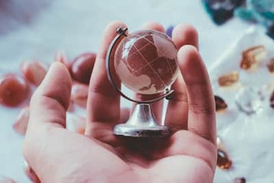 hand holding a small, glass globe, considering global liability insurance