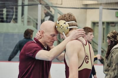 a wrestling coach embraces a wrestler for encouragement