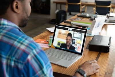 a man at a computer, holding a video conversation with a woman