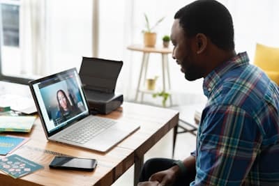 a man in front of a computer, speaking to someone on video