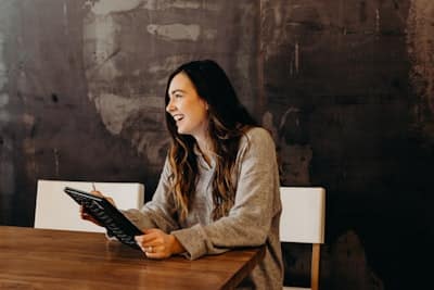 a woman at a table laughing, with a notebook