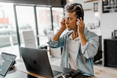 man putting on headphones, in front of laptop