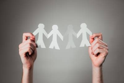 a person holding up a string of paper people