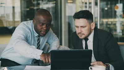 two people conversing over a laptop