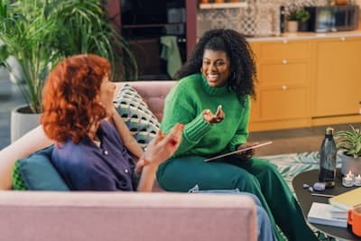two women conversing on a coach