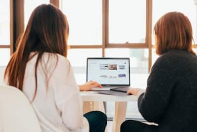 two women sitting at a laptop