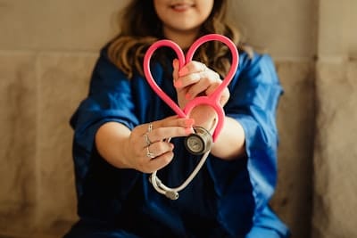 a woman holding a stethoscope in the shape of a heart