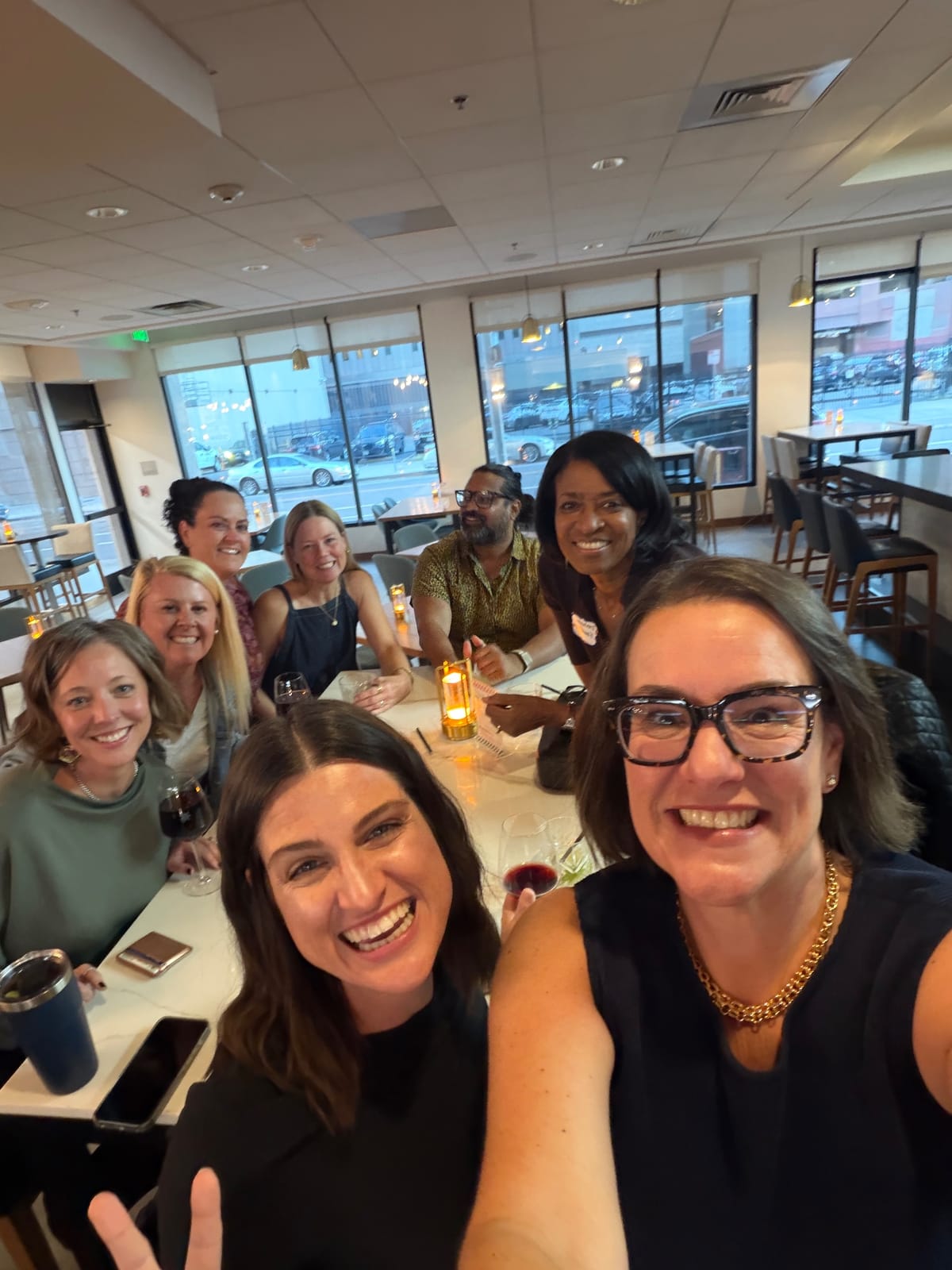 Eight Ignite attendees smile for a selfie around a candlelit table at dinner in Denver
