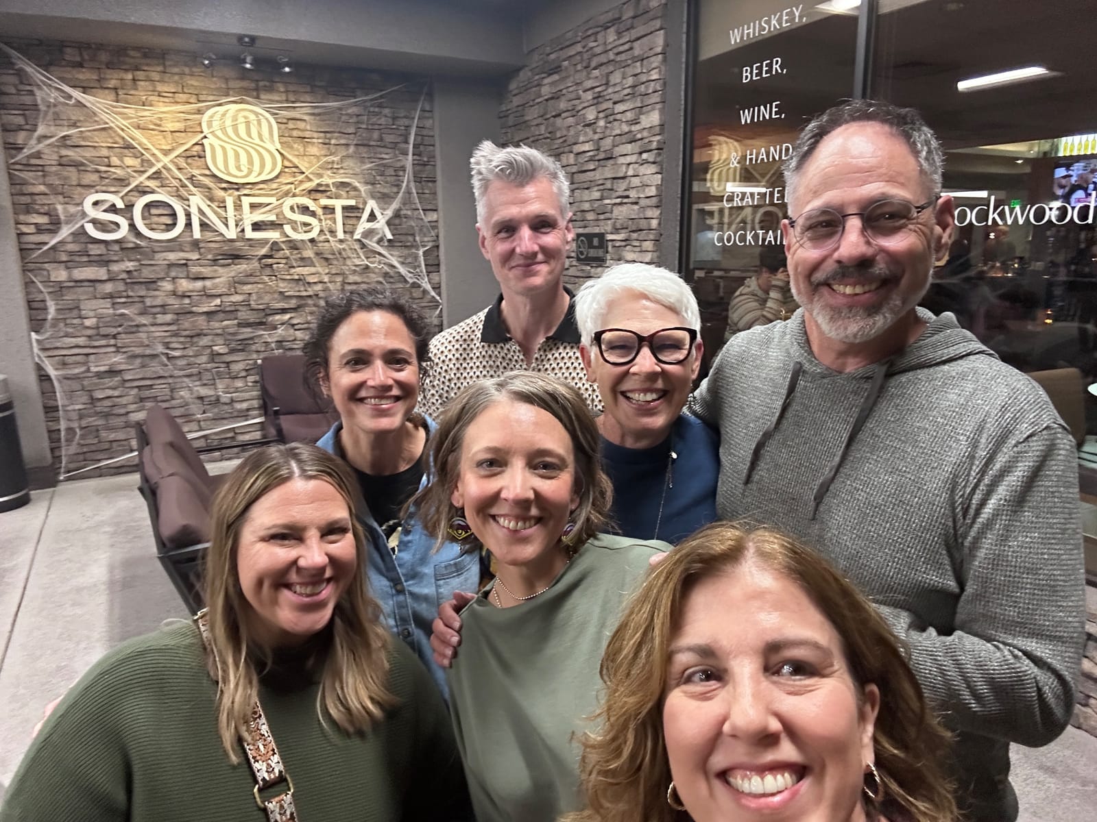 Seven attendees take a nighttime selfie outside the Sonesta hotel in Denver